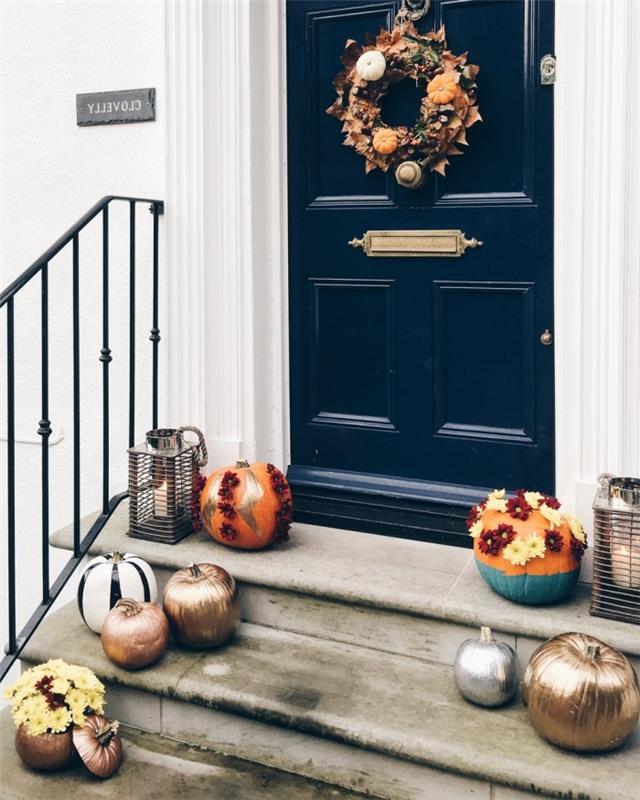 mörkblå ytterdörr och vit husfasad, krans gjord av frukt och torkade löv för Halloween