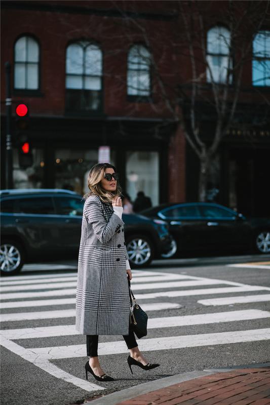 امرأة تمشي في الشارع ، توقعات الموضة لعام 2019 ، مرتدية بنطالًا أسود وكعبًا ، معطف طويل منقوش بالأبيض والأسود