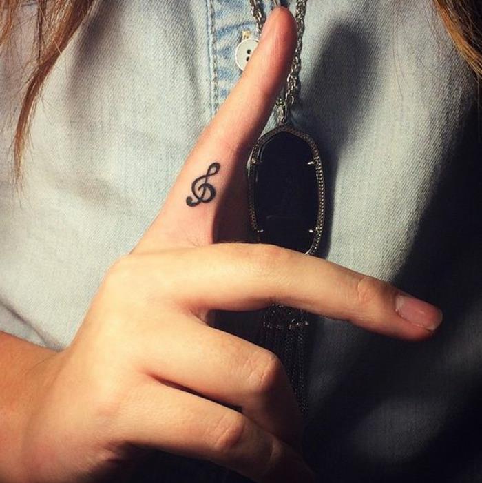 en tatuering på fingret med ett musikaliskt motiv, ganska diskret diskanttatuering