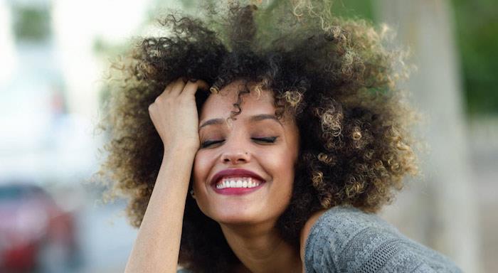 účes pre kučeravé vlasy afro žena prírodná metisse s blond končekmi