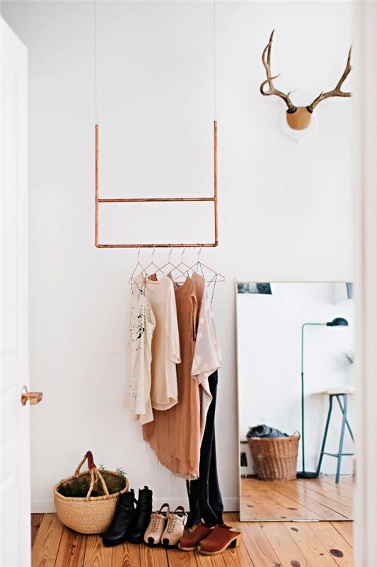 منطقة خلع الملابس مع خزانة ملابس نحاسية بسيطة معلقة من السقف ومرآة كبيرة مستطيلة موضوعة على الحائط