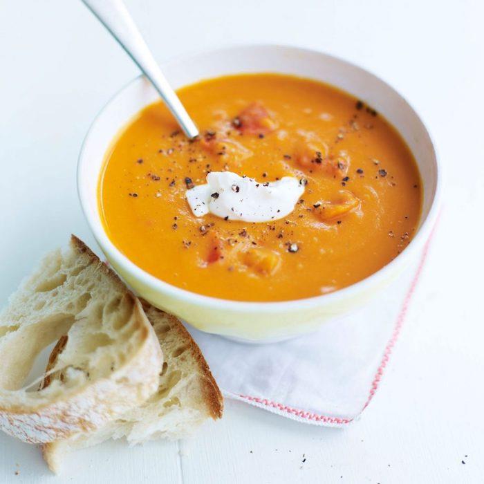 Ricetta vellutata di zucca ، ciotola con minestra e panna ، pezzettini di pane vicino alla ciotola