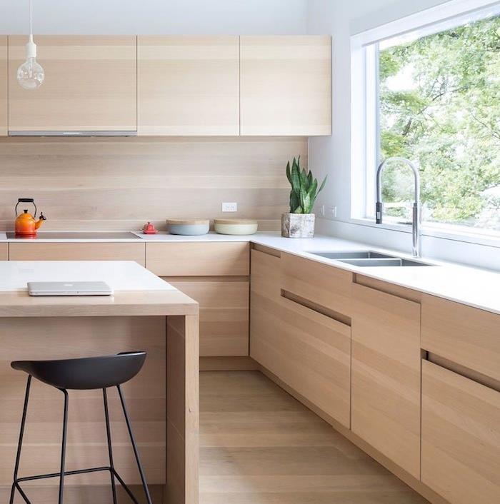 مطبخ خشبي مع وحدات عالية ومنخفضة من الخشب الفاتح وجزيرة خشبية مركزية وأرضية خشبية وكرسي أسود