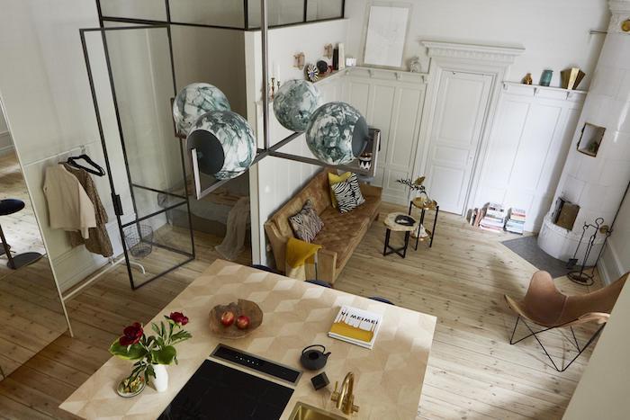 vägg och glastak för att skilja ett sovrum från resten av studion, gul och brun soffa, fällstol, modern öppen spis, designkök och original hängande ljus