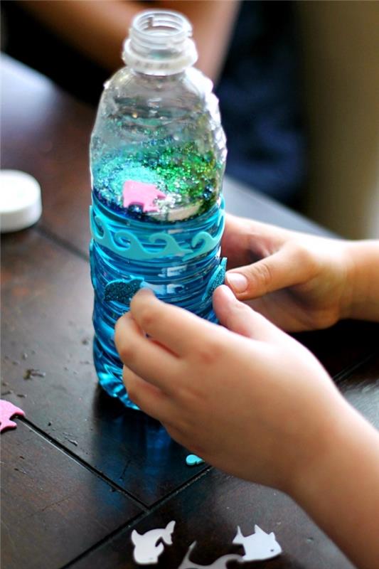 gör sensoriska flaskor, Montessori flaskemodell på havsbottentemat med färgat vatten och djurfigur