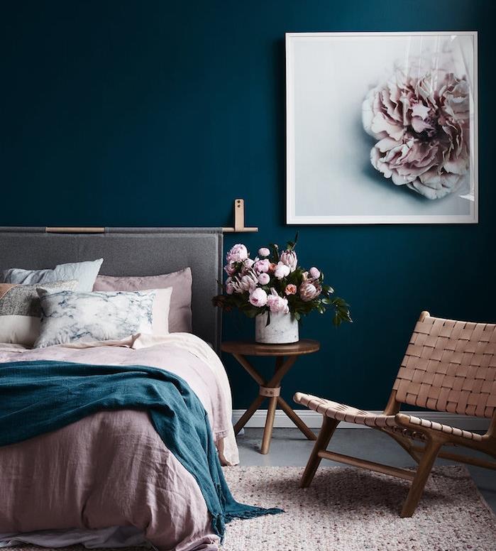 maľba spálne pre dospelých tmavo modrá farba, ružová, modrá a biela posteľná bielizeň, kreslo, medený konferenčný stolík, s kyticami váz vo váze, rám na maľovanie kvetov
