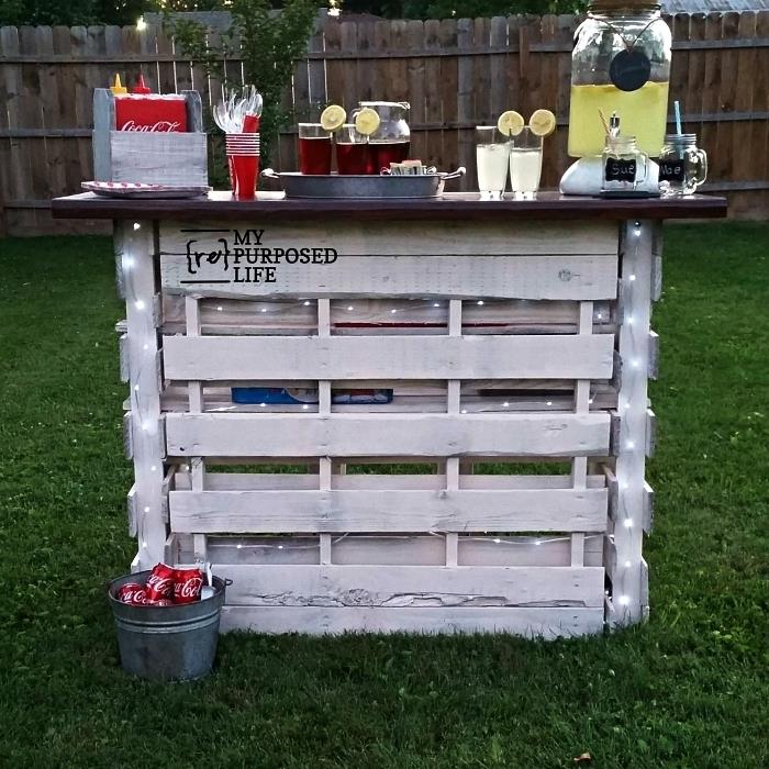 bygga en bar i återvunnet trä för trädgården, limonadstång i pall ommålad i vitt upplyst av en ledkrans