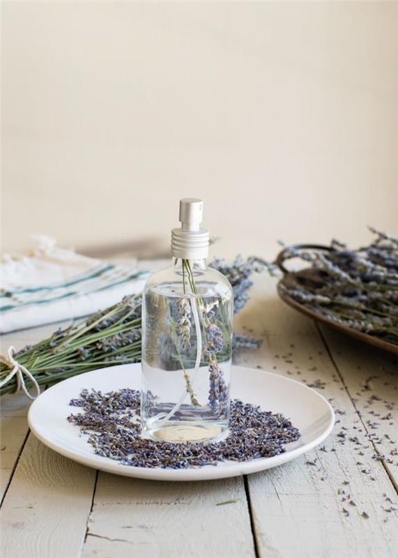 hur man gör lavendel vattenspray i tallrik med lavendelblommor på träbord