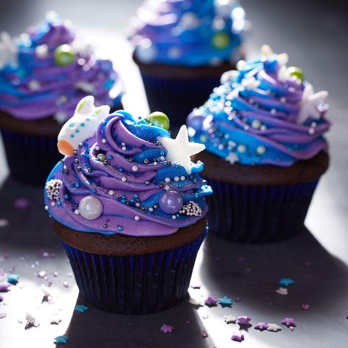 domáce čokoládové košíčky s dekoráciou z maslového krému v modrej a fialovej galaxii a dekoráciou farebných guličiek a hviezd