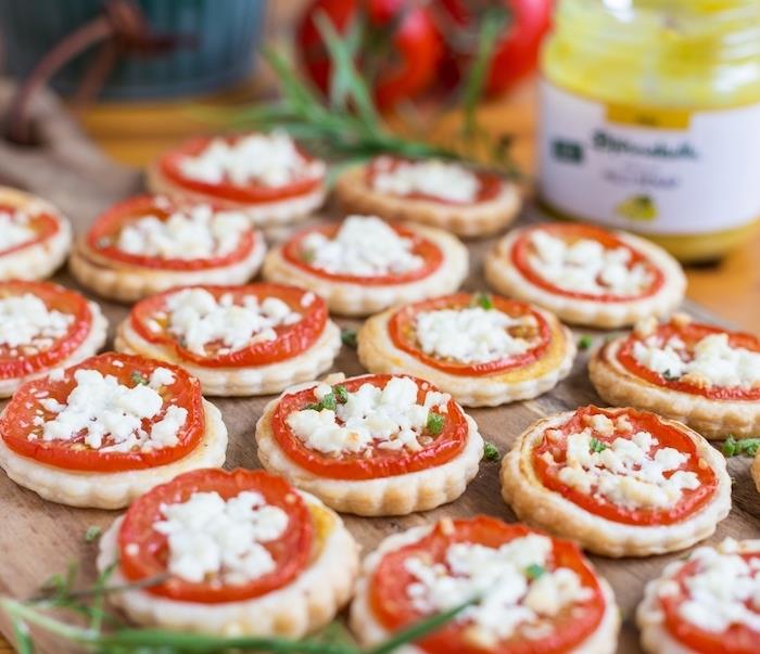 ukážkový aperitív toast, polena z lístkového cesta s plátkom paradajok a fety, ozdobená čerstvými bylinkami