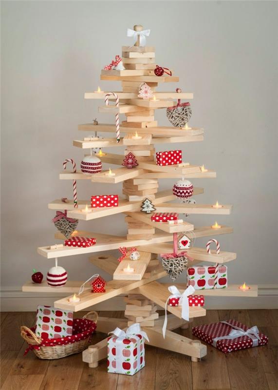 Vianočný stromček v bielych drevených doskách, malé darčeky oblečené v dekoratívnom papieri, malé led sviečky, malé domčeky