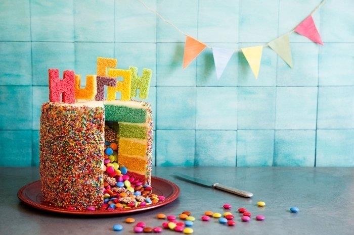 original barnfödelsedagstårtid idé om flera lager färgglad sockerkaka dekorerad med bokstäver från den kvarvarande kakan