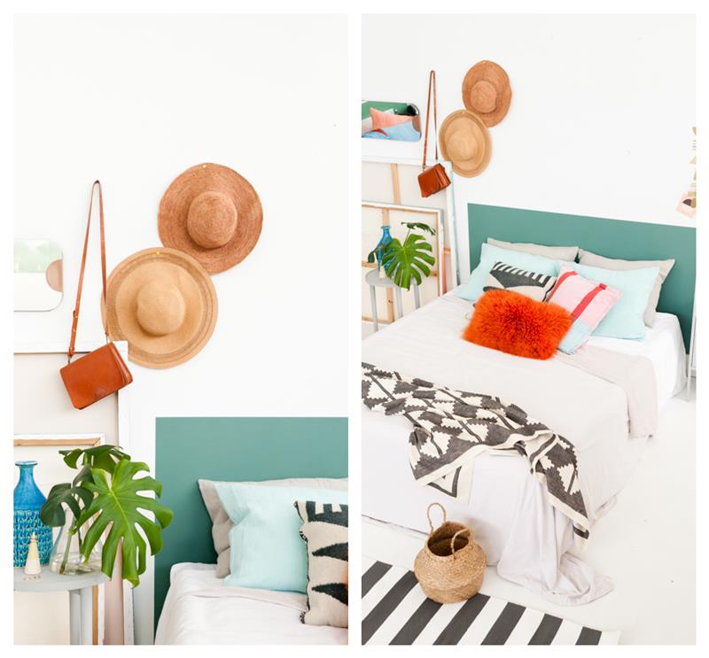 sänggaveldekoration i skogsgrön färg, dekorativa kuddar, svartvita sängkläder, hattar, vas och växter dekoration på ett vitt nattduksbord
