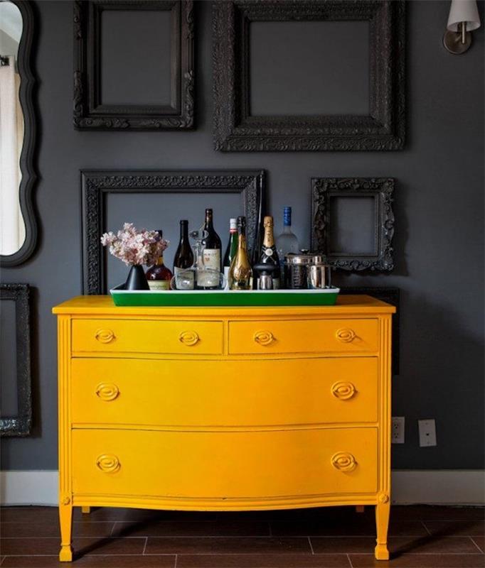 farba na nábytok, vintage žltá komoda s antracitovo sivou podkladovou stenou zdobenou čiernymi rámami