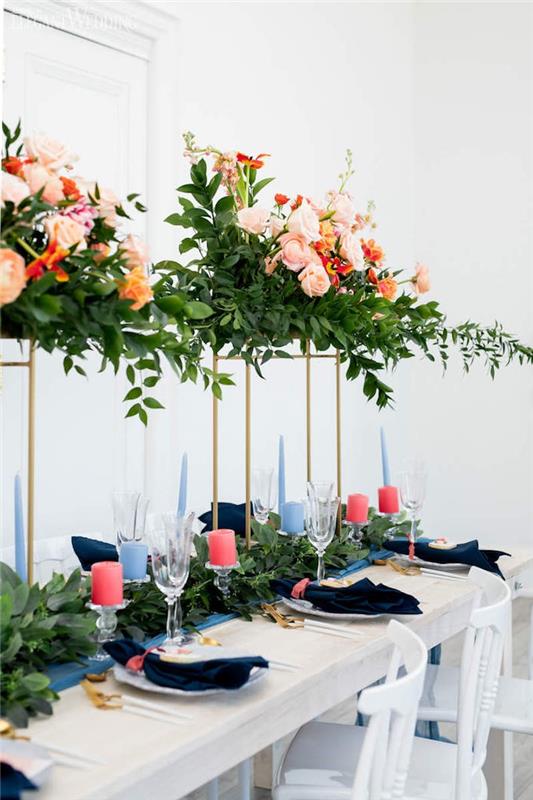 vysoké svadobné kvetinové usporiadanie na zlatých stĺpoch, behúň na stôl so zeleným lístím a ružovými sviečkami na sklenených držiakoch, nápad na elegantnú svadobnú výzdobu