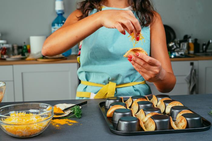 Piatti messicani, tacos con ripieno, formaggio grattugiato, donna che cucina