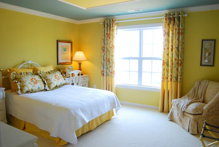 nápad, ako vyzdobiť svoju spálňu v žltej farbe, kvetinové vzory na závesoch a posteľných vankúšoch, biely koberec, biela komoda