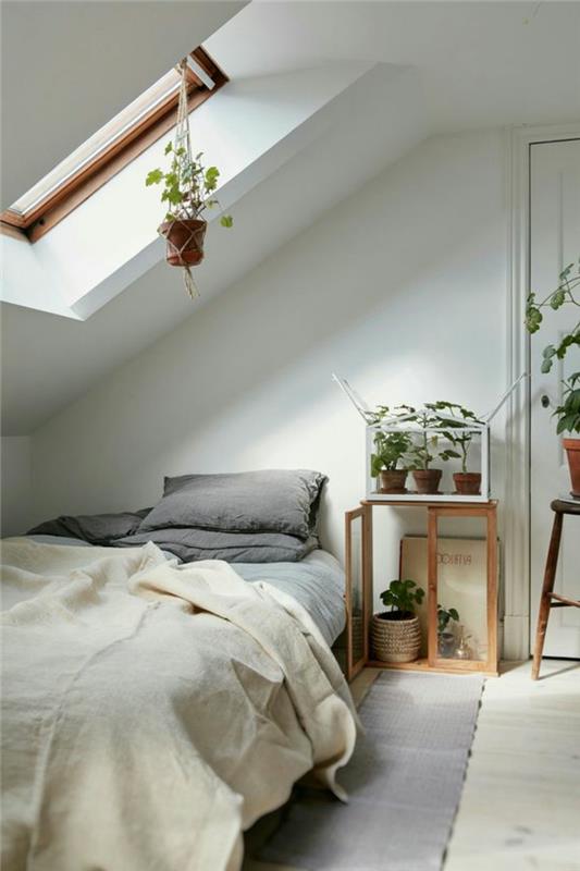sluttande sovrumsinredning, vit parkett, vit väggfärg, växter, blommig inredning, grå matta och kuddar, benvitt sängklädsel
