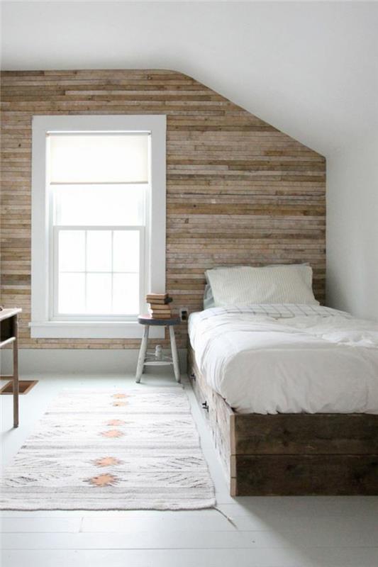 träpanel accentvägg, vit färgfärg, mönstrad grå matta, träsäng, vita sängkläder, stort nattduksbord, träpall, vinds layout