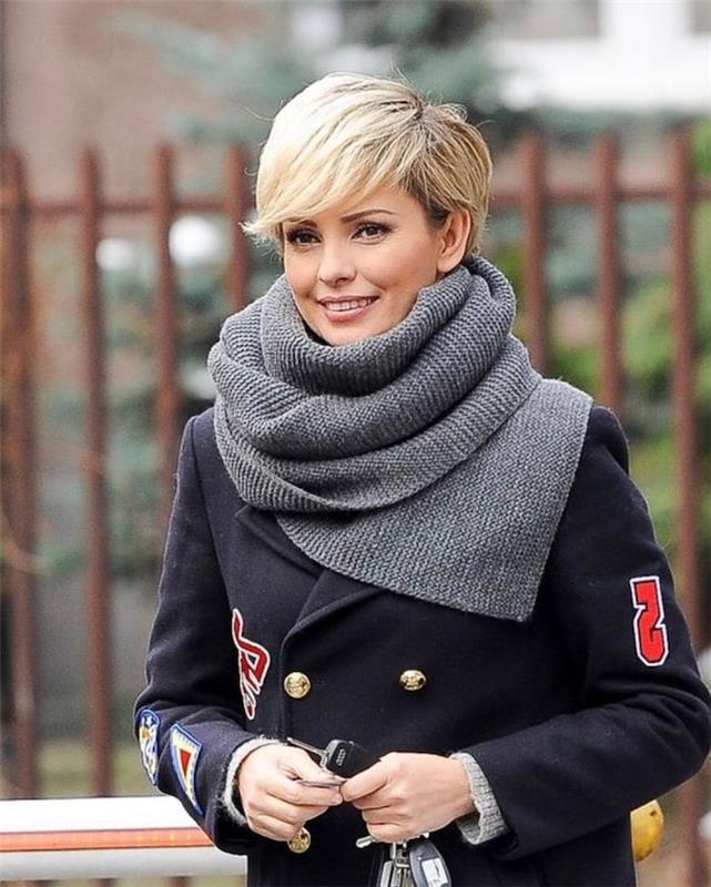 blond krátky strih s blond zúženou ofinou v šedej šatke a čiernom kabáte