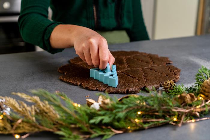 Använd en kakskärare för att göra julsmörbröd i form av ett julgranrecept, pepparkakor