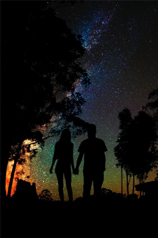 خلفية جميلة مع زوجين شابين في حالة حب تحت سماء مرصعة بالنجوم ، وفكرة الحب وخلفية النجوم للهاتف