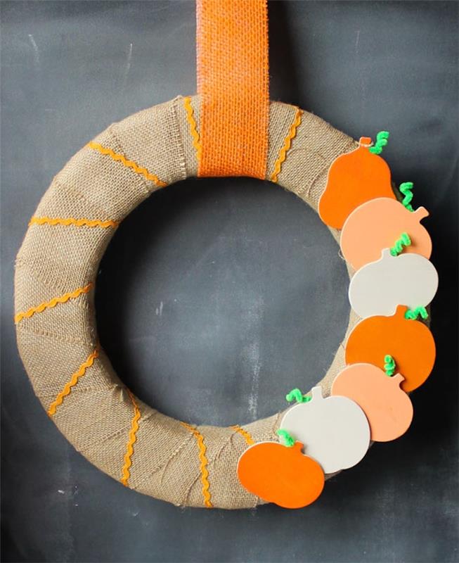 نموذج من إكليل الخريف في دائرة الطحالب مزينة بشريط من الجوت مع ديكو من تماثيل اليقطين الخشبية مع تعليق على شريط الجوت البرتقالي