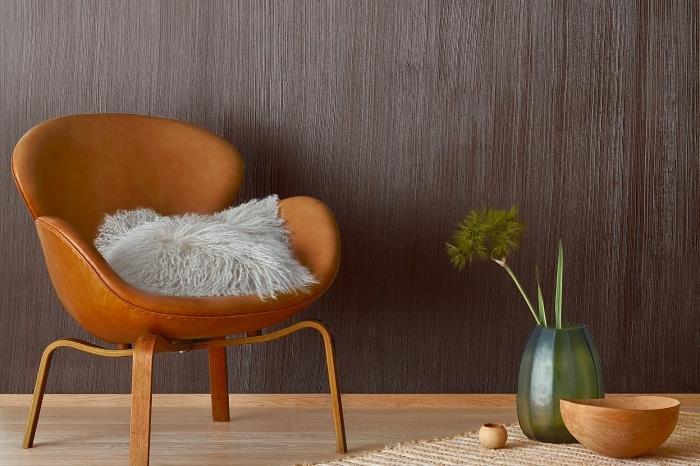 exotická dekorácia do obývačky s parketami zo svetlého dreva a efektovou stenou, príklad farby imitácie tmavého dreva, model koženej stoličky s drevenými nohami
