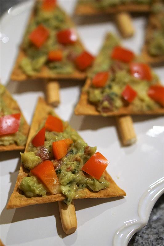 triangelformade kex, avokado och tomater ovanpå, enkla veganska aptitretare, i en vit tallrik