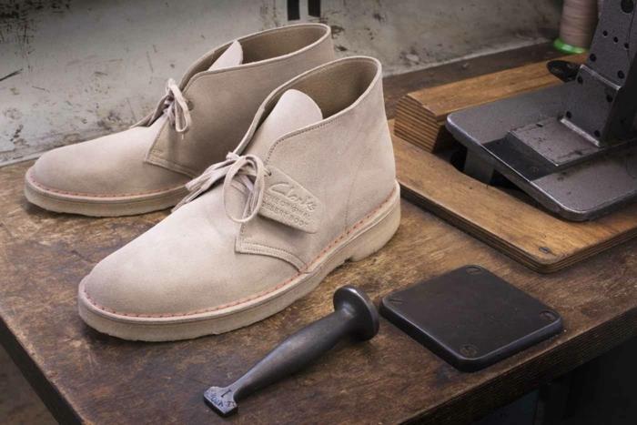 زوج من الأحذية ذات اللون الكريمي الباهت ، مع أربطة حذاء من تيد ، أحذية غير رسمية للأعمال ، ترتكز على سطح خشبي ، بتفاصيل معدنية