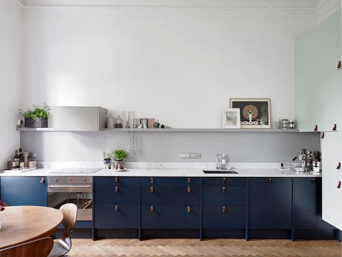 litet kök, mörkblå målade köksmöbler i trä med vit marmorbänk