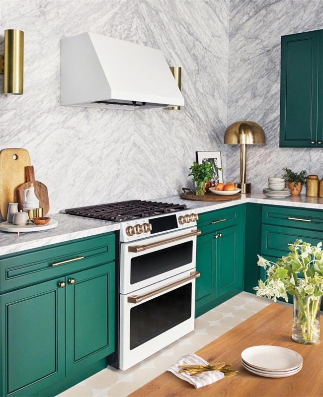 نموذج مطبخ معاصر بجدران من الرخام الأبيض ومزودة بخزائن ظل خضراء ولمسات ذهبية