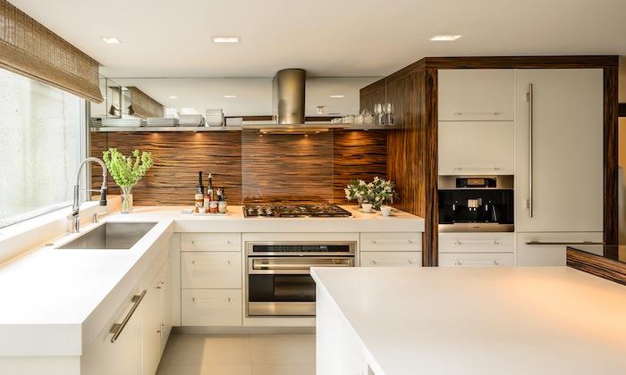 vit köksmodell med brun träplatta, vita möbler och vitvaror i rostfritt stål, grått klinkergolv