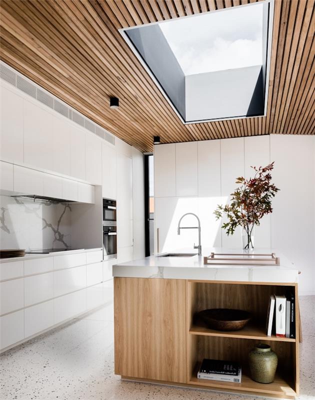 utrustat kök, träbänk och tak, vitt köksskåp med marmorstänk, trädgrenar i en vas