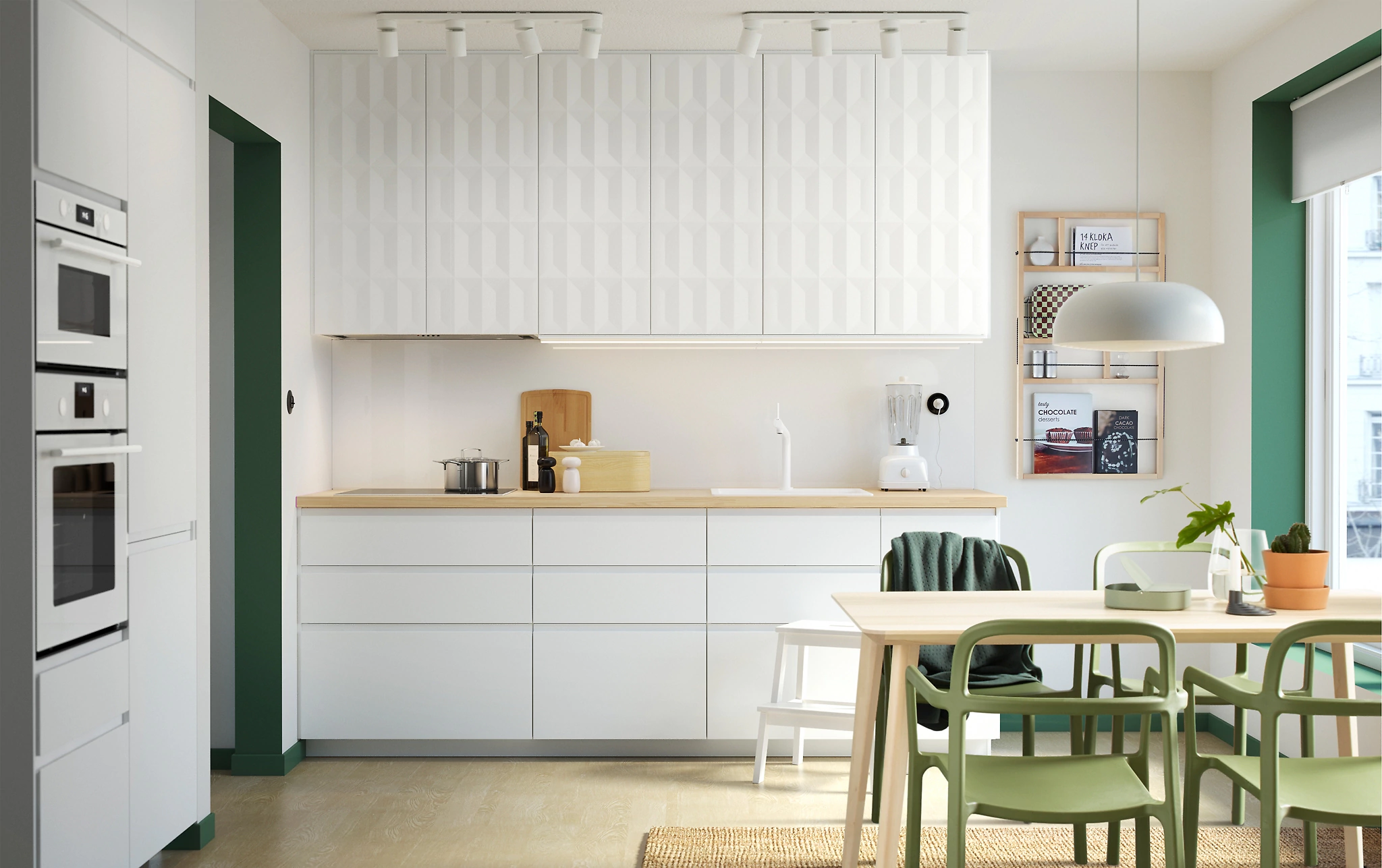 vitt kök med bänkskivor i trä, vitt underskåp och gråvitt högskåp, ljus parkett, matplats med träbord och gröna stolar