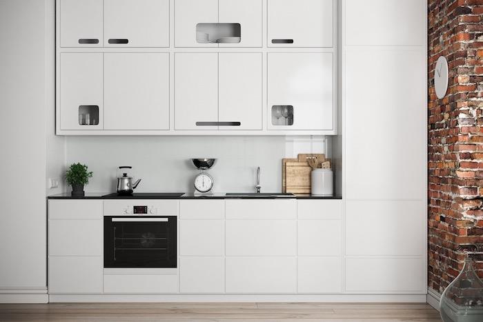 vitlackerat kök helt i vitt med en kontrasterande svart ugn, tegelvägg och ljus träparkett, modern industridesign