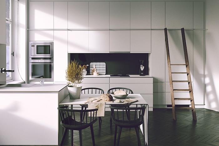 vitt utrustat kök med svart stänk, mörkbrun parkett, vitt köksskåp och ö, trästege, vitt bord och svarta stolar