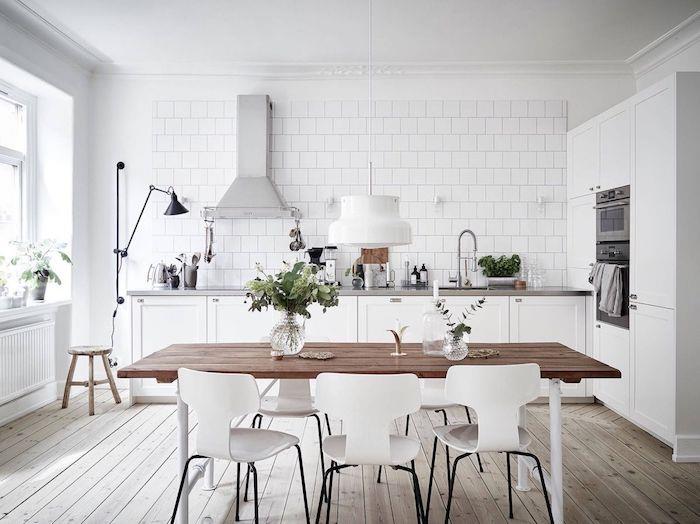 vitt utrustat kök med grå bänkskiva, vita kakel, ljus parkett, vita stolar, rostfri dammsugare, skandinavisk stil