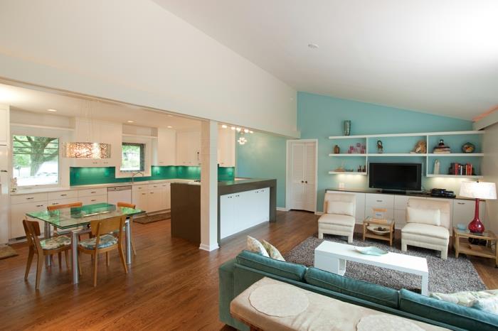 litet kök med vit fasad, grön stänk, brun parkett, matsal med glasbord och trästolar, havsgrön soffa, vitt soffbord, grå matta, vita fåtöljer, vitt tv -skåp, blå accentvägg