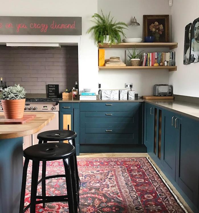 نموذج مطبخ ريفي أنيق باللون الأزرق البترولي على خزانة المطبخ والجزيرة المركزية والجدار الأبيض ، سجادة حمراء شرقية