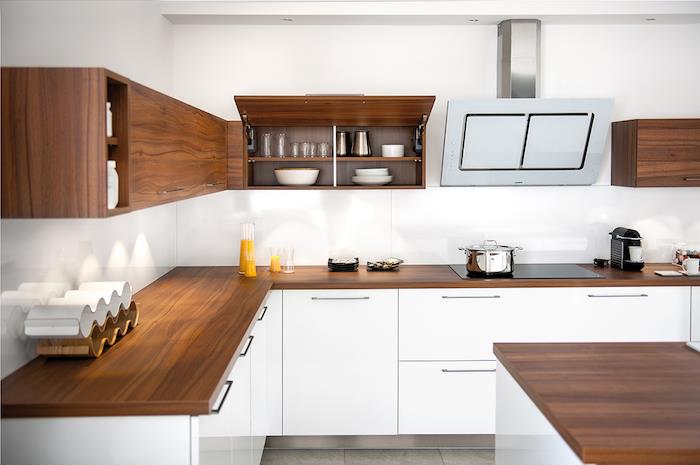 vitt kök med bänkskivor i trä, köksskåp och stänkskiva i vitt, träväggar, grått klinkergolv, enkel design