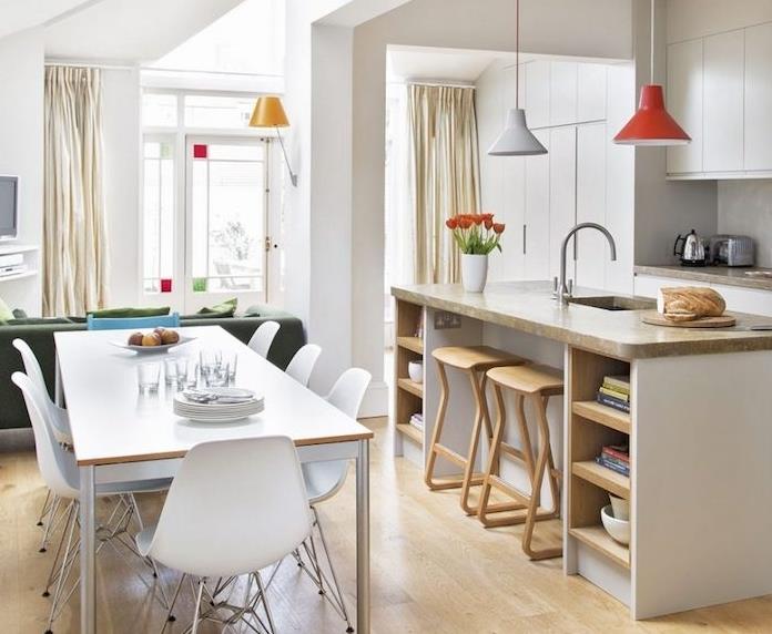 utrustat kök med vitt skåp, centralö med grå bänkskiva, ljus parkett, liten matsal med skandinaviskt bord och stolar