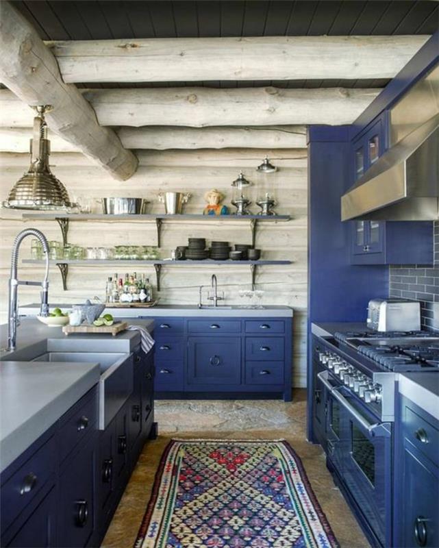 kačacia modrá skrinka, sivé stropné trámy, sivé drevené obkladové steny z PVC, kačacia modrá skrinka, obdĺžnikový koberec v etno štýle so svetlými farbami