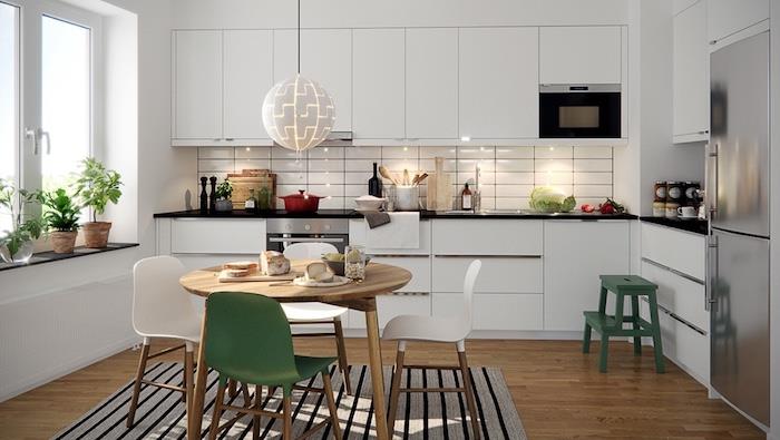 vitt lackerat kök med vita höga och låga möbler, brun träaftett, träbord omgivet av vita och gröna stolar, grå och svart matta, hängande ljusboll