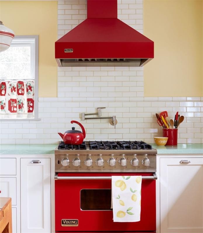 ديكور مطبخ عتيق أنيق ريفي مع جدار أصفر ، بلاط أبيض حب الشباب ، مكنسة كهربائية وموقد أحمر ، واجهة خزانة بيضاء