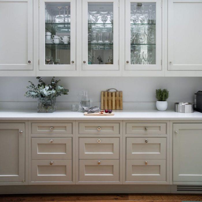 لوحة أمامية للمطبخ باللون الرمادي الفأر ودواليب بيضاء عالية ، سطح عمل أبيض ، نباتات خضراء مزخرفة