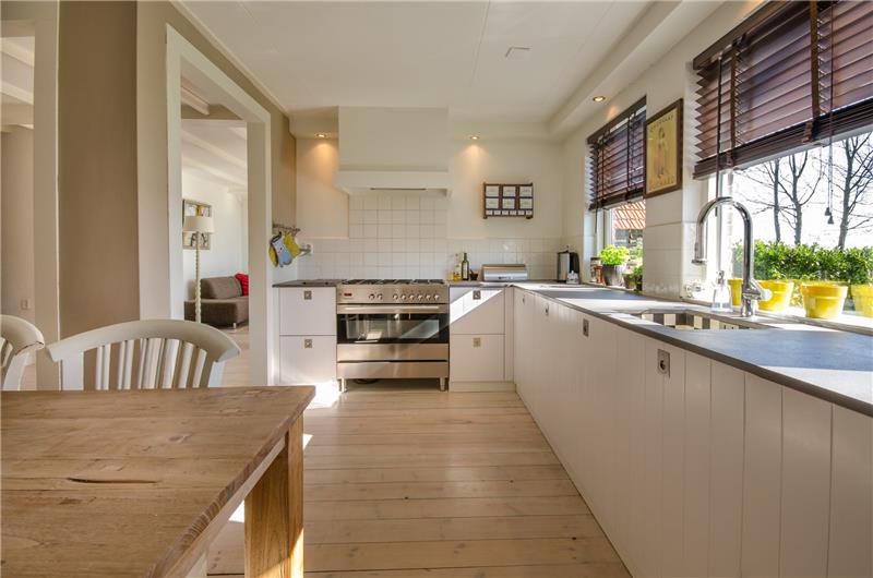trendová kuchyňa 2018 s bielou nízkou skrinkou, stolíkom a podlahou zo svetlého dreva, bielymi stenami, sivou vintage rúrou