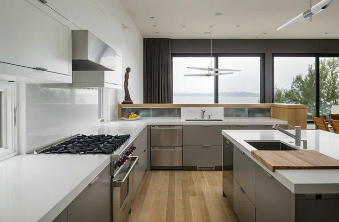 تصميم مطبخ مطلي باللون الأبيض ونوافذ كبيرة ومساحة مفتوحة للمطبخ على شكل حرف L.
