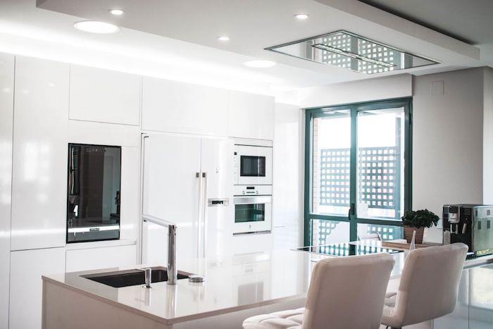 exempel på ett vitlackerat kök, vitt köksskåp, grå centralö och grå stolar, grön ramad dörr