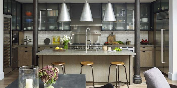kuchyňa oddelená obývacia izba sivým barom s drevenými stoličkami okolo, drevenými kuchynskými a kovovými skriňami so sklenenými dverami, dekorom v industriálnom štýle